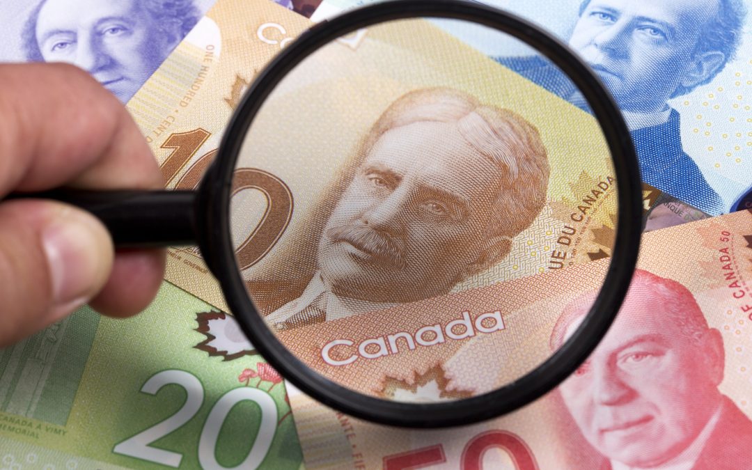 Canadian dollars in a magnifying glass